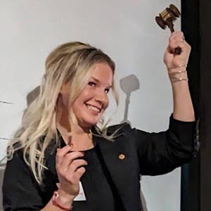 A smiling Nicole Benton raises gavel.