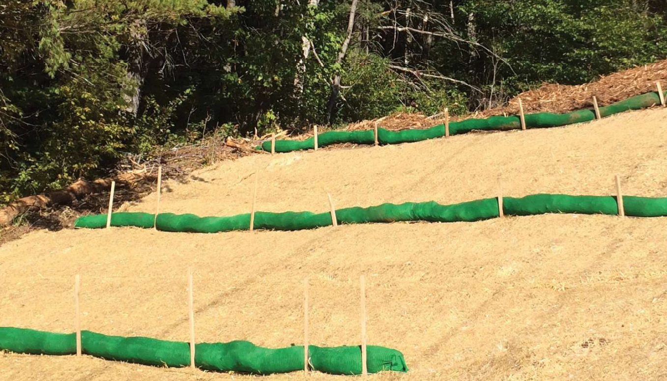 Filter socks (a manufactured tube filled with shredded material) slow stormwater runoff on long open slopes.