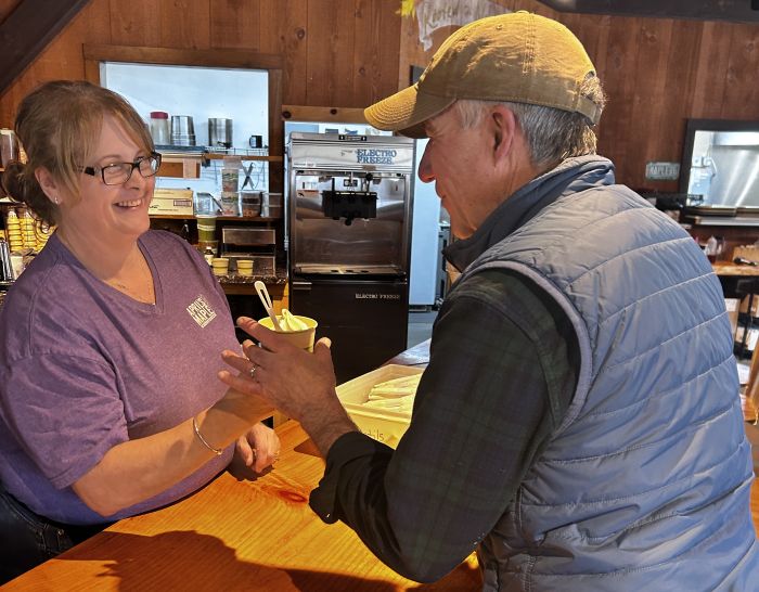 April Lemay hands a maple creemee in a cup to Governor Scott in Canaan Wednesday.