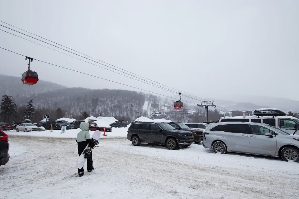 A snowboarder heads to their car after a day at Stowe Mountain Resort. February 17, 2024. Photo by Sophie Acker