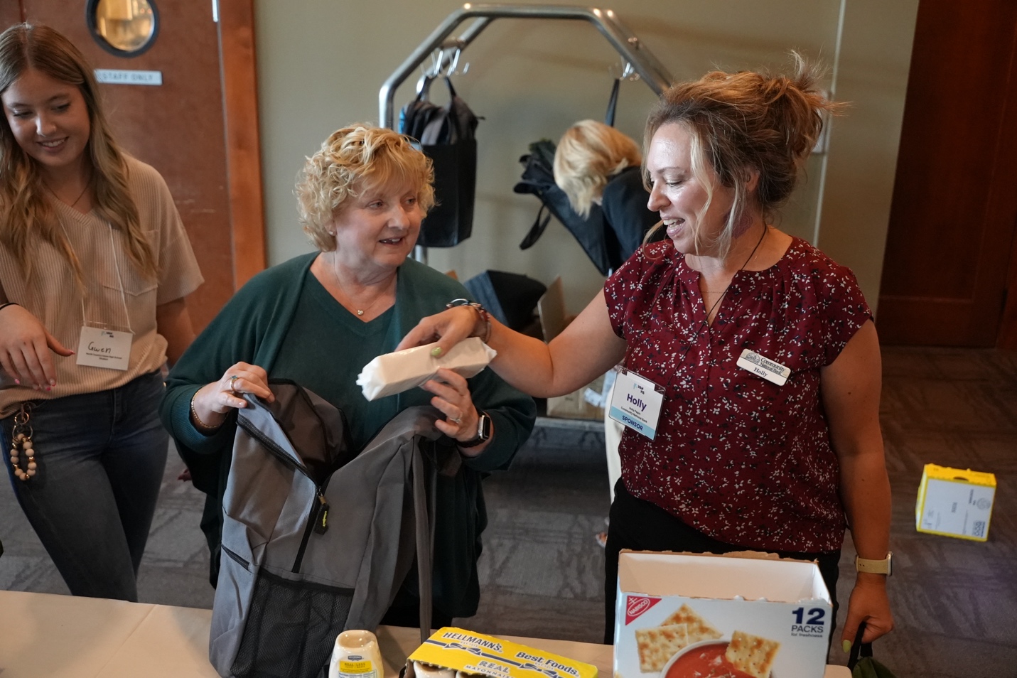 VAHHS outgoing board chair Anna Noonan, president and COO of Central Vermont Medical Center works with Community National Bank officer Holly Pepin on filling a “vacation kit” for North Country Career Center’s community fridge as student Gwen Roberge looks on.