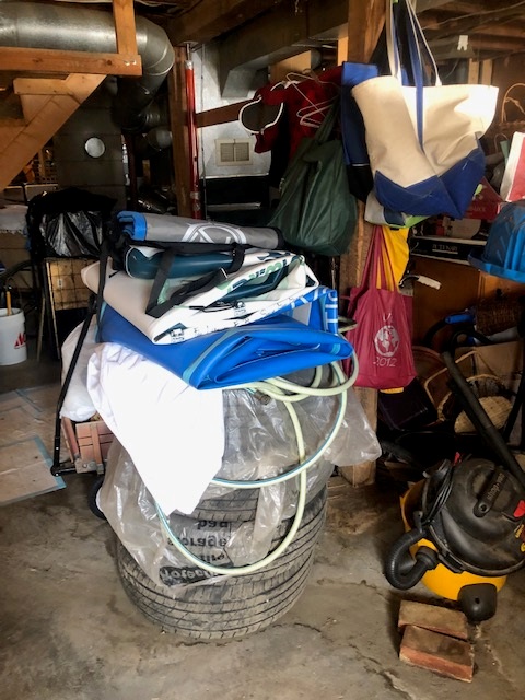 A basement filled with tires, a vacuum cleaner, and other items.
