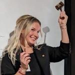 A smiling Nicole Benton raises gavel.