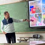 Man teaching class while pointing to PPT presentation
